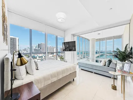 a bedroom with a bed a large window and couch