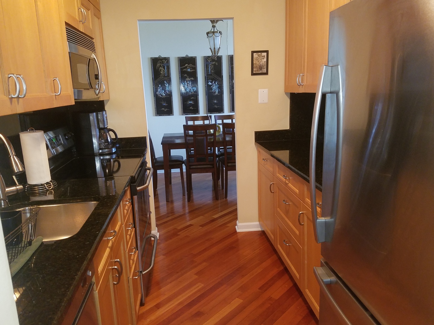 Undisclosed Address Chicago, IL 60613 - Photo 15 of 16 a kitchen with stainless steel appliances granite countertop a refrigerator a stove and a sink with wooden floor
