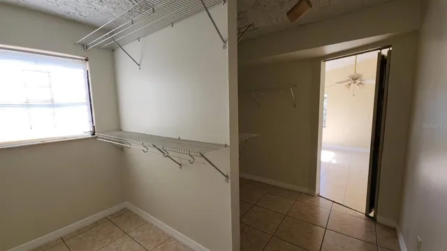an empty room with windows and chandelier fan