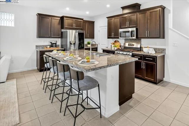 a kitchen with stainless steel appliances a sink a stove a microwave a refrigerator and cabinets