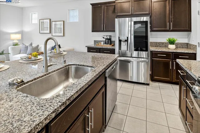 a kitchen with granite countertop a sink a stove and refrigerator
