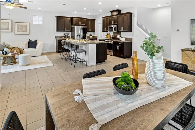 a living room with stainless steel appliances furniture wooden floor and a view of kitchen