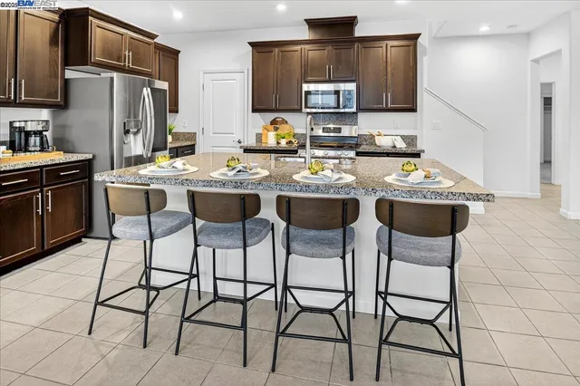 a kitchen with stainless steel appliances kitchen island granite countertop a sink and a refrigerator