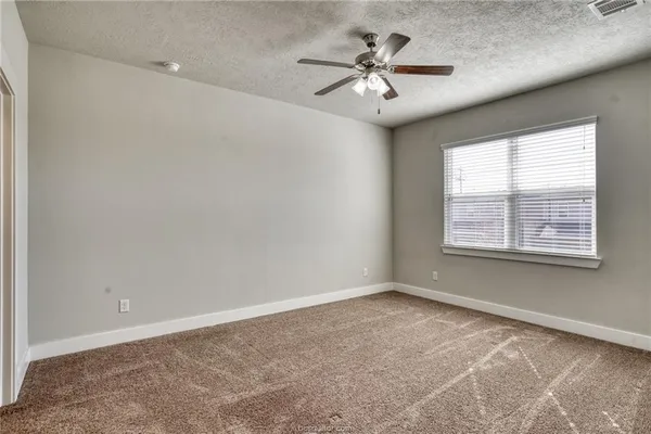 an empty room with a chandelier fan and windows