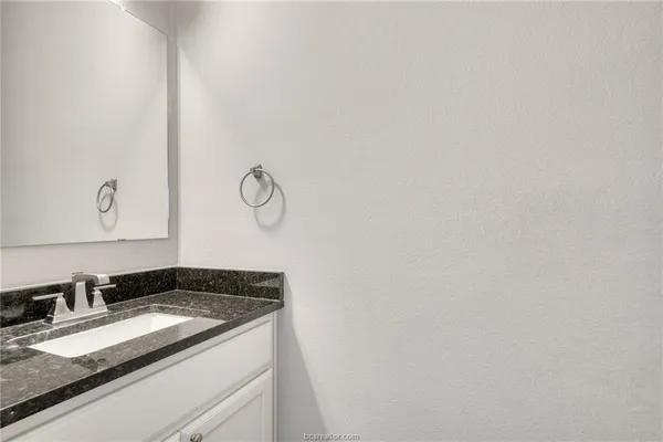a bathroom with a granite countertop sink and vanity