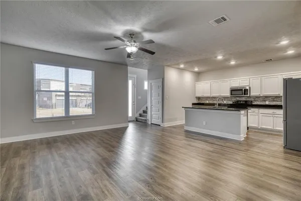 a view of kitchen with refrigerator stove and wooden floor