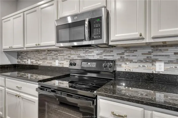 a kitchen with granite countertop a stove and a microwave