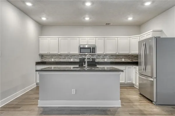 a kitchen with kitchen island stainless steel appliances a sink stove and refrigerator