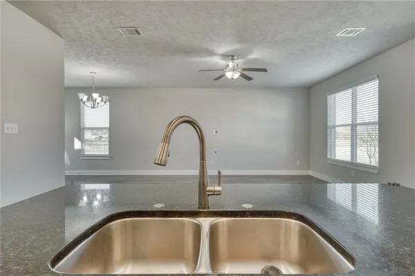 a close view of a faucet a sink a faucet a window and a chandelier