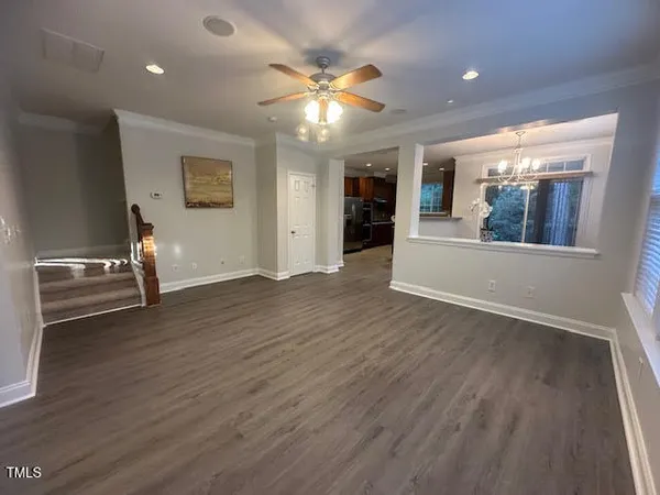 a view of an empty room with wooden floor and a ceiling fan