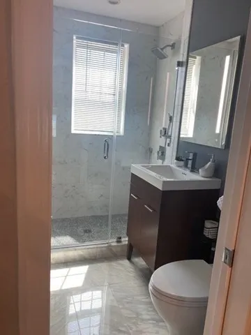 a bathroom with a sink a toilet a mirror and shower