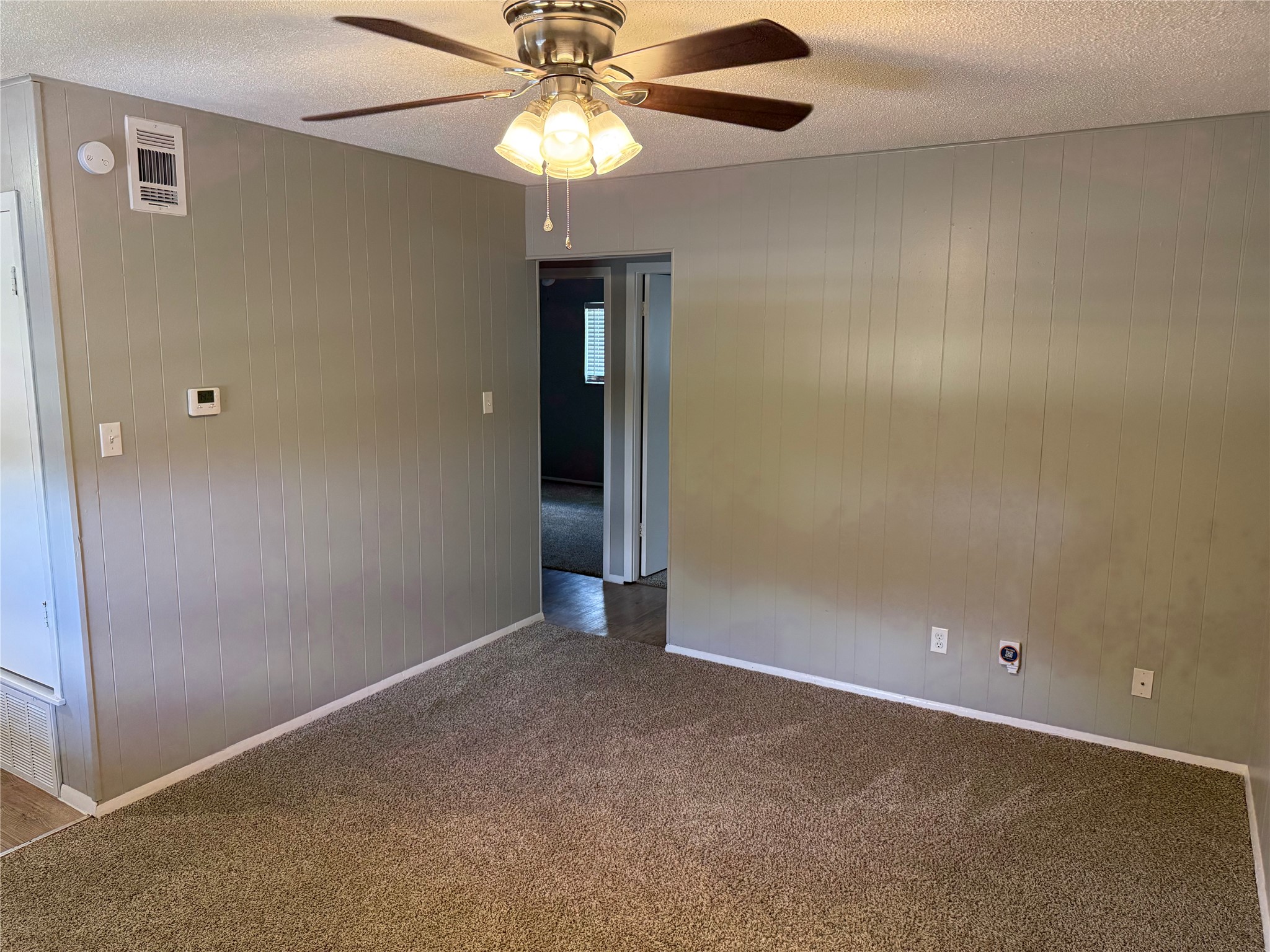 1209 Vance Street, Unit 45 Taylor, TX 76574 - Photo 7 of 32 Carpeted spare room with wood walls, ceiling fan, and a textured ceiling