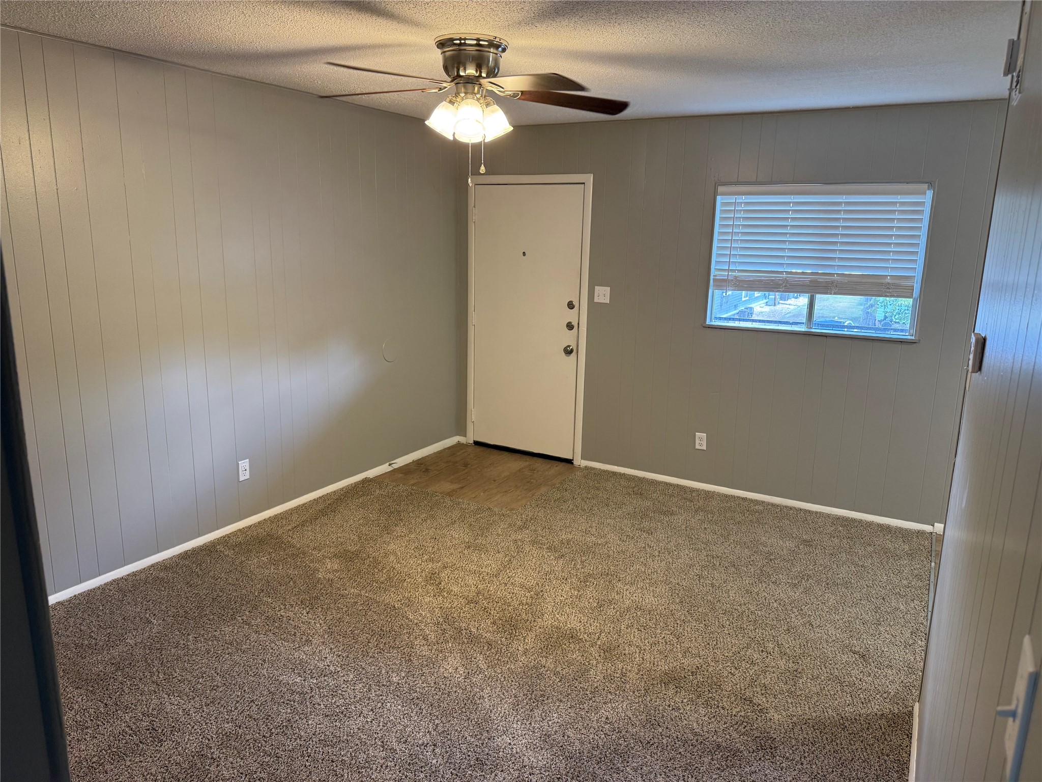 1209 Vance Street, Unit 45 Taylor, TX 76574 - Photo 8 of 32 Empty room with wood walls, carpet, a ceiling fan, and a textured ceiling