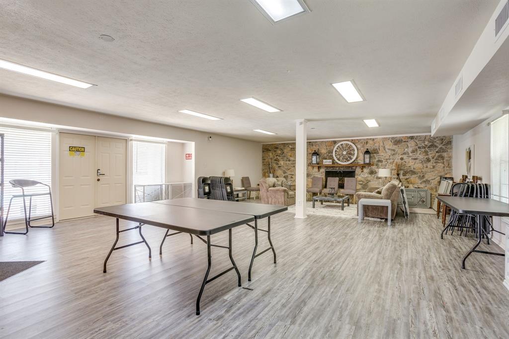 4102 Ridglea Country Club Drive, Unit 1503 Fort Worth, TX 76126 - Photo 18 of 21 Spacious multi-purpose room featuring wood-finish flooring, recessed lighting, and a stone accent wall with a built-in fireplace, Community rec room by the pool