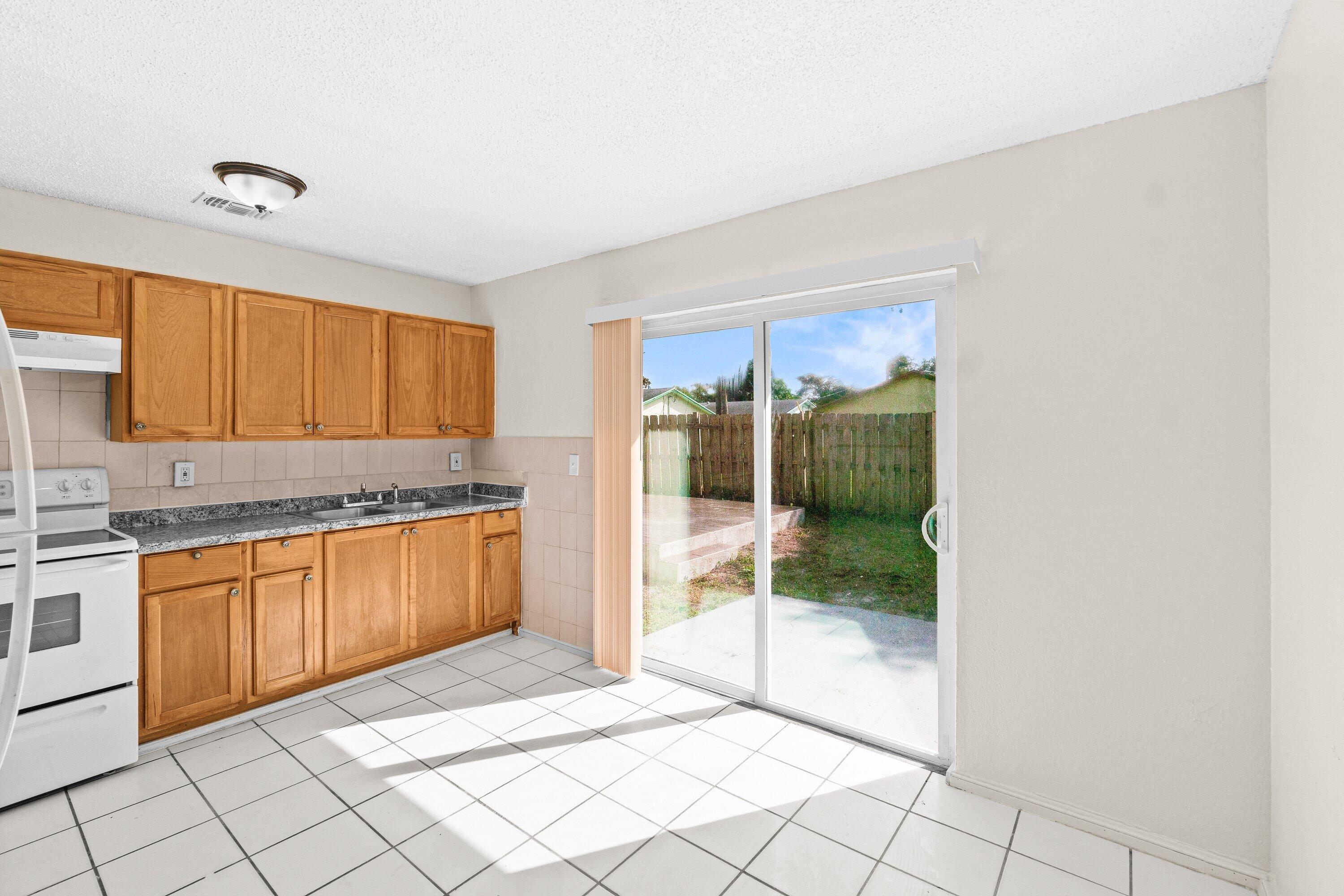 4869 Gulfstream Road Lake Worth, FL 33461 - Photo 4 of 20 a kitchen with granite countertop a refrigerator and white cabinets