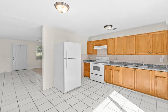 a kitchen with granite countertop a refrigerator and a sink