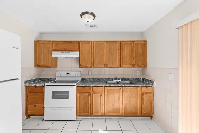 a kitchen with a stove a sink and white cabinets