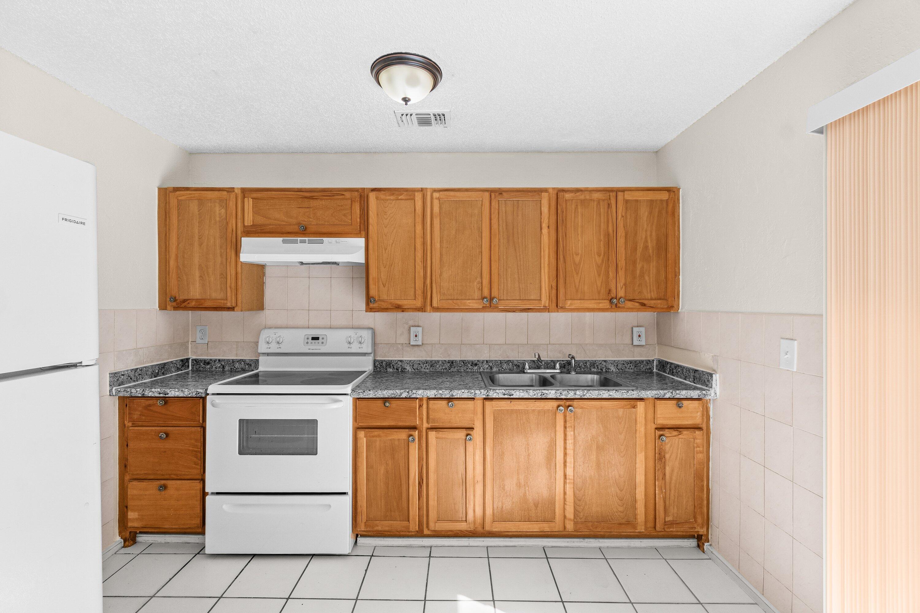 4869 Gulfstream Road Lake Worth, FL 33461 - Photo 6 of 20 a kitchen with a stove a sink and white cabinets