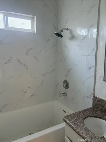 a bathroom with a granite countertop bathtub shower and vanity
