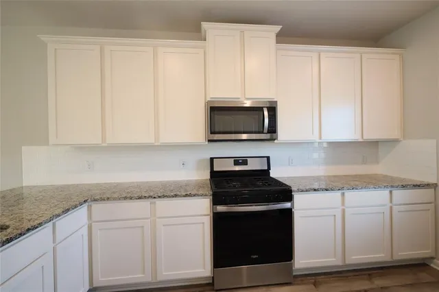 a kitchen with white cabinets and black appliances
