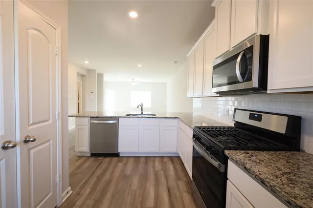 a kitchen with granite countertop a sink stove and refrigerator