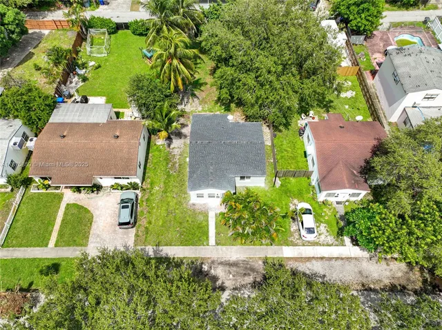 an aerial view of residential house with outdoor space and trees all around