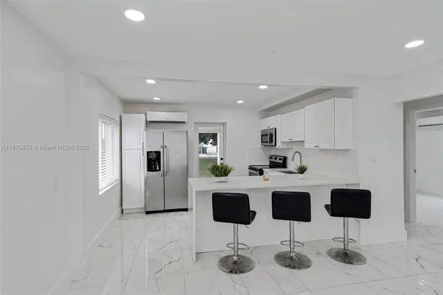 a kitchen with stainless steel appliances kitchen island granite countertop a dining table chairs and refrigerator