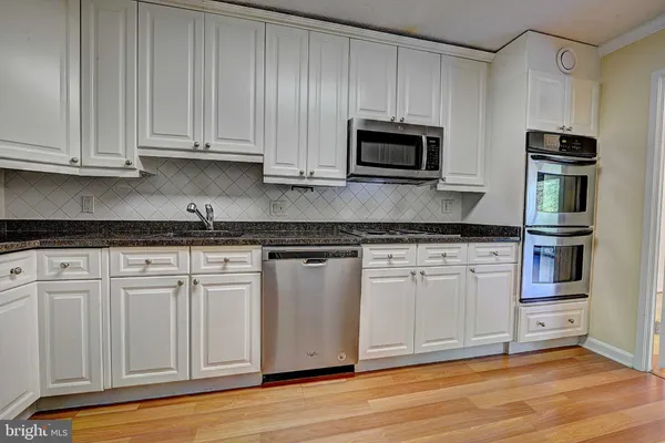 a kitchen with granite countertop white cabinets and stainless steel appliances