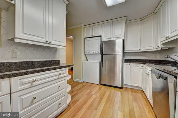 a kitchen with a refrigerator and white cabinets