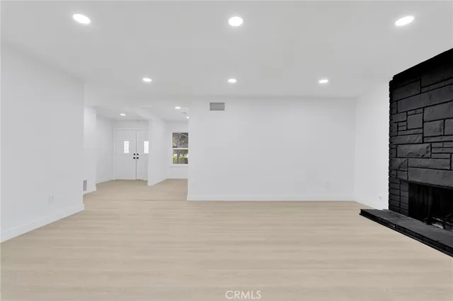 a view of empty room with wooden floor and fireplace