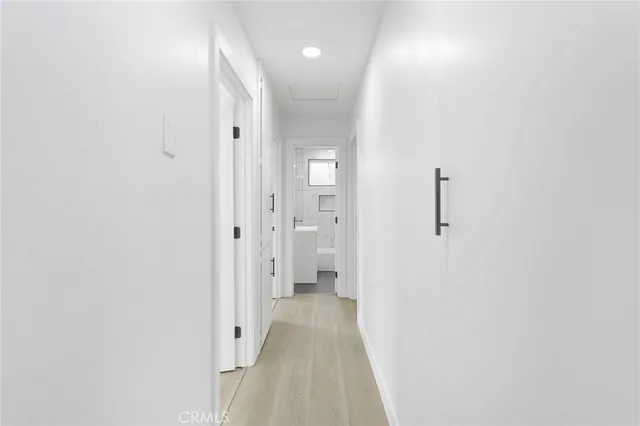 a view of a hallway with wooden floor and a bathroom