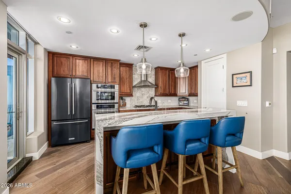 a kitchen with stainless steel appliances granite countertop a refrigerator a sink dishwasher a stove and a refrigerator with wooden floor