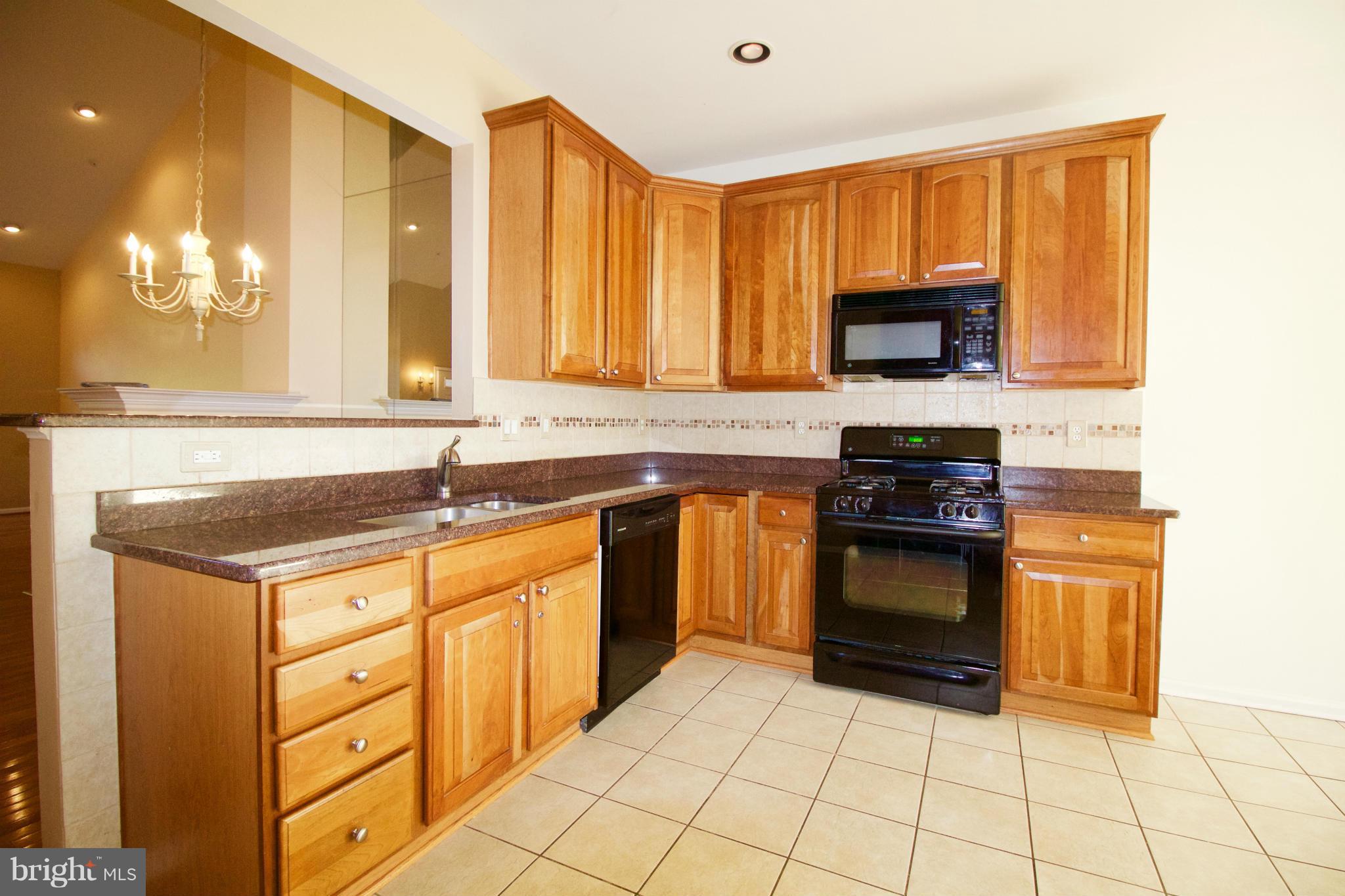 8411 Meadowsweet Road Pikesville, MD 21208 - Photo 6 of 30 a kitchen with stainless steel appliances granite countertop a stove a sink and a microwave