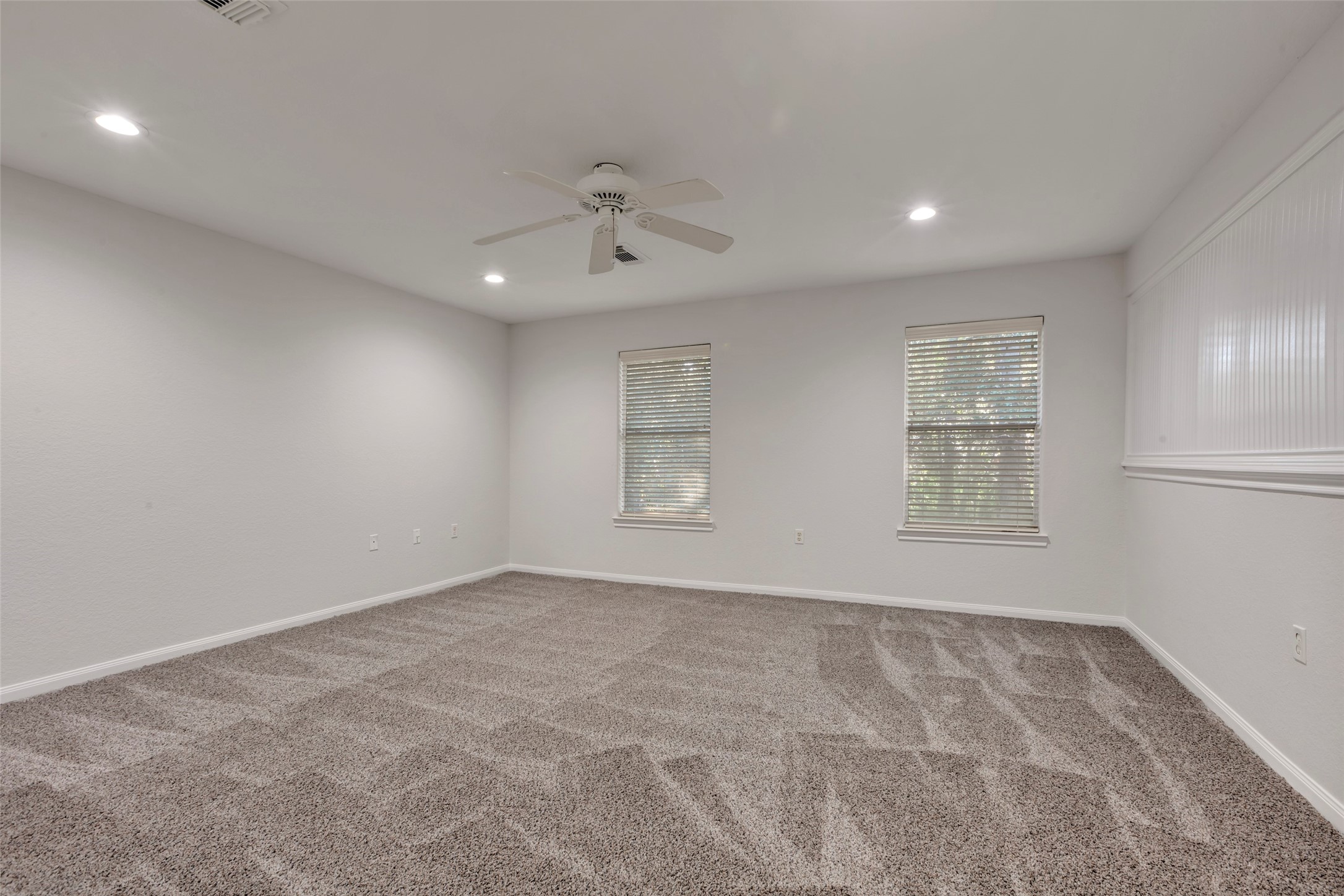 770 Hunt Road, Unit 212 Baytown, TX 77521 - Photo 32 of 40 This is a spacious, well-lit room featuring plush carpeting, two windows with horizontal blinds, a ceiling fan, and recessed lighting. It has neutral-colored walls and ample wall space for customization.