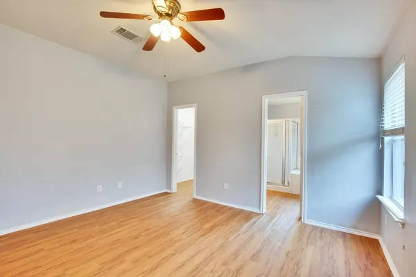 a view of an empty room with window and wooden floor