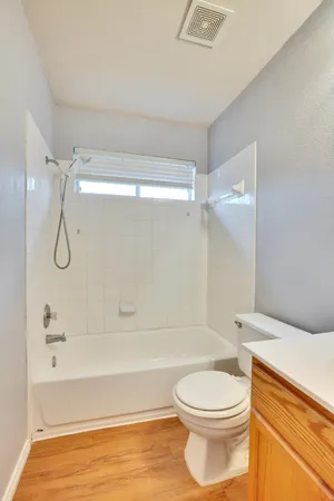 an empty room with wooden floor fan and windows
