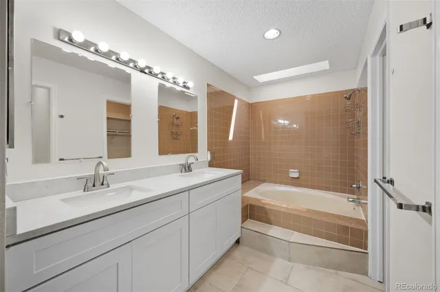a bathroom with a bathtub shower sink double vanity and a mirror
