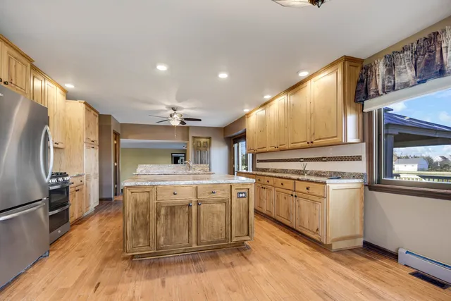 a kitchen with stainless steel appliances granite countertop a refrigerator a sink a stove and a wooden floors