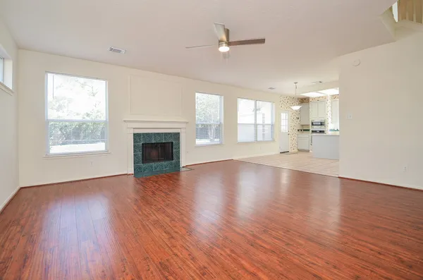 an empty room with wooden floor fireplace and windows