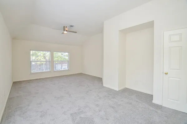 an empty room with windows and ceiling fan