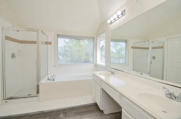 a bathroom with a double vanity sink large mirror and a bathtub