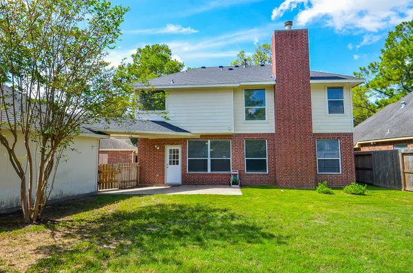 a view of a brick house with a large window and a large tree with plants