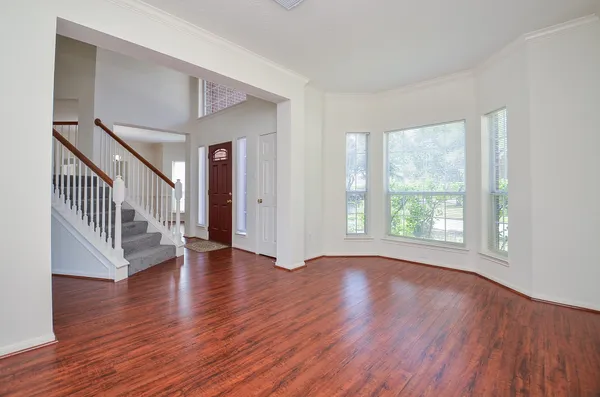 a view of an empty room with wooden floor and a window