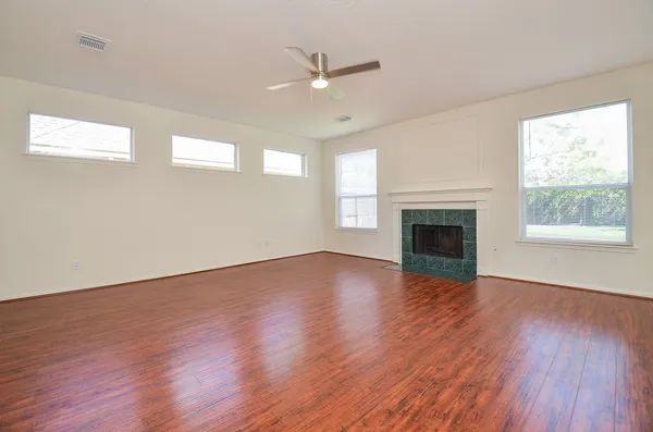 a view of an empty room with wooden floor and a fireplace