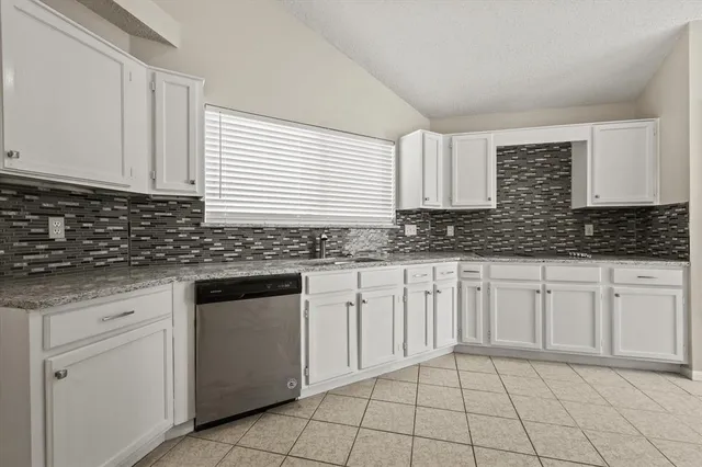 a kitchen with granite countertop white cabinets sink and stainless steel appliances