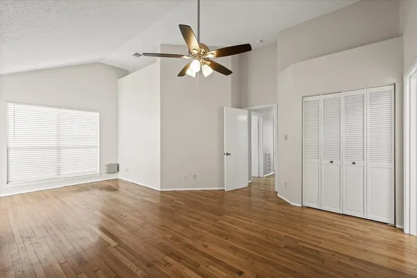 an empty room with wooden floor closet and windows