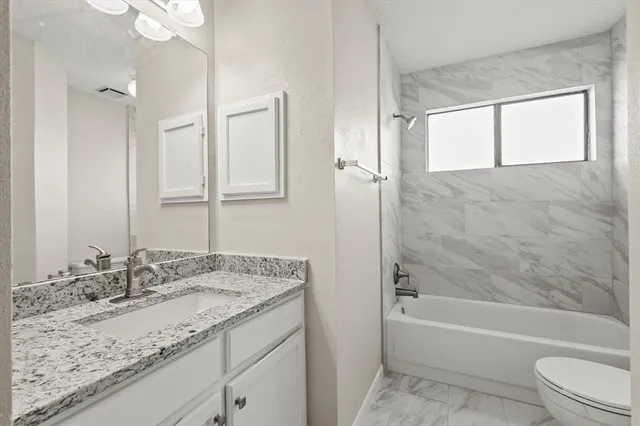 a bathroom with a granite countertop sink mirror toilet and bathtub