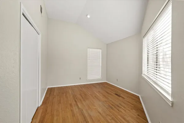 a view of empty room with wooden floor and fan