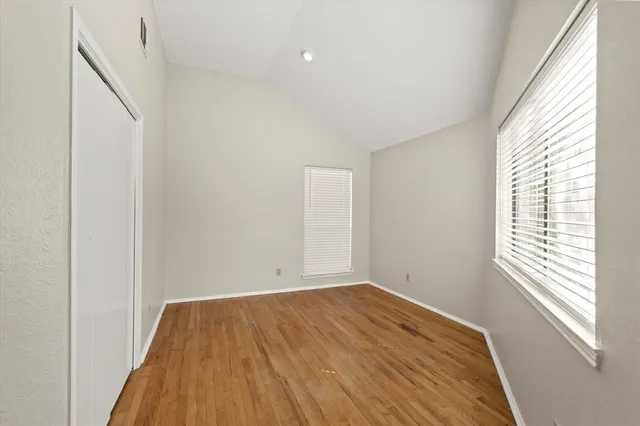 a view of empty room with wooden floor and fan
