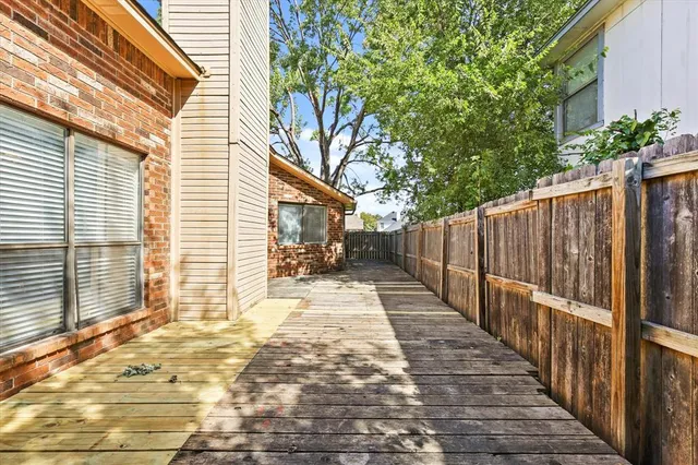 a view of a backyard with wooden fence and large trees